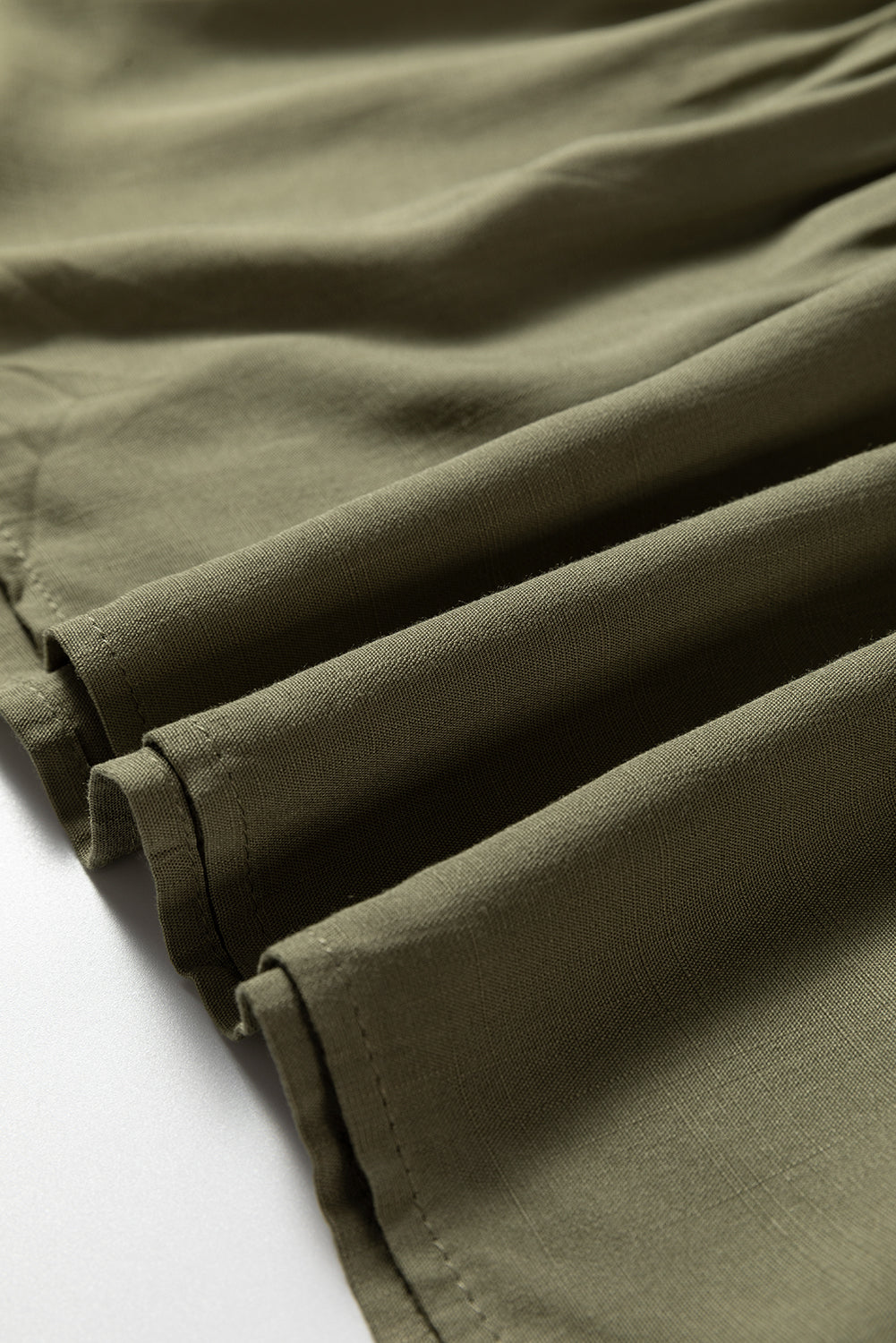 Close-up of olive green lightweight fabric with stitched hem and soft texture