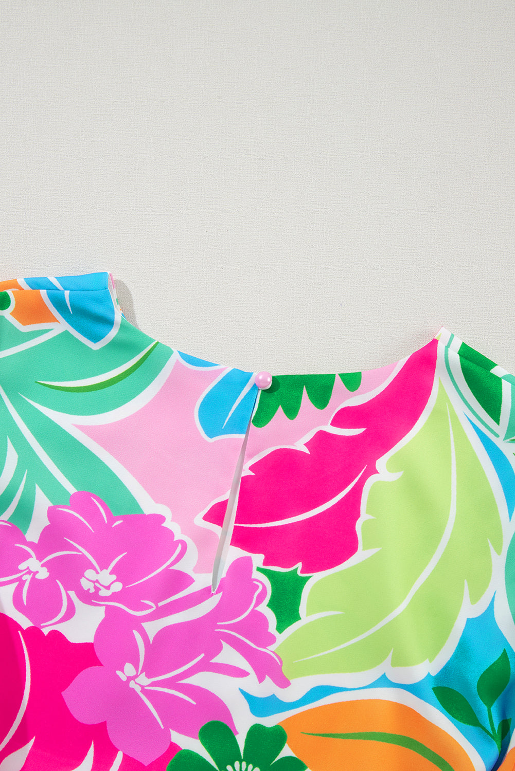 Close-up of colorful floral patterned blouse with round neckline and back button detail