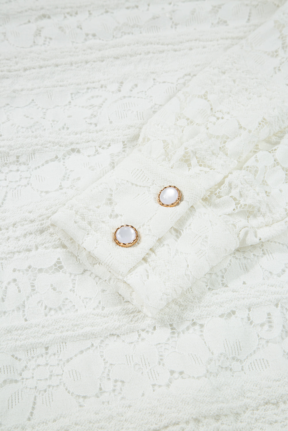 White lace blouse sleeve with floral pattern and two pearl buttons