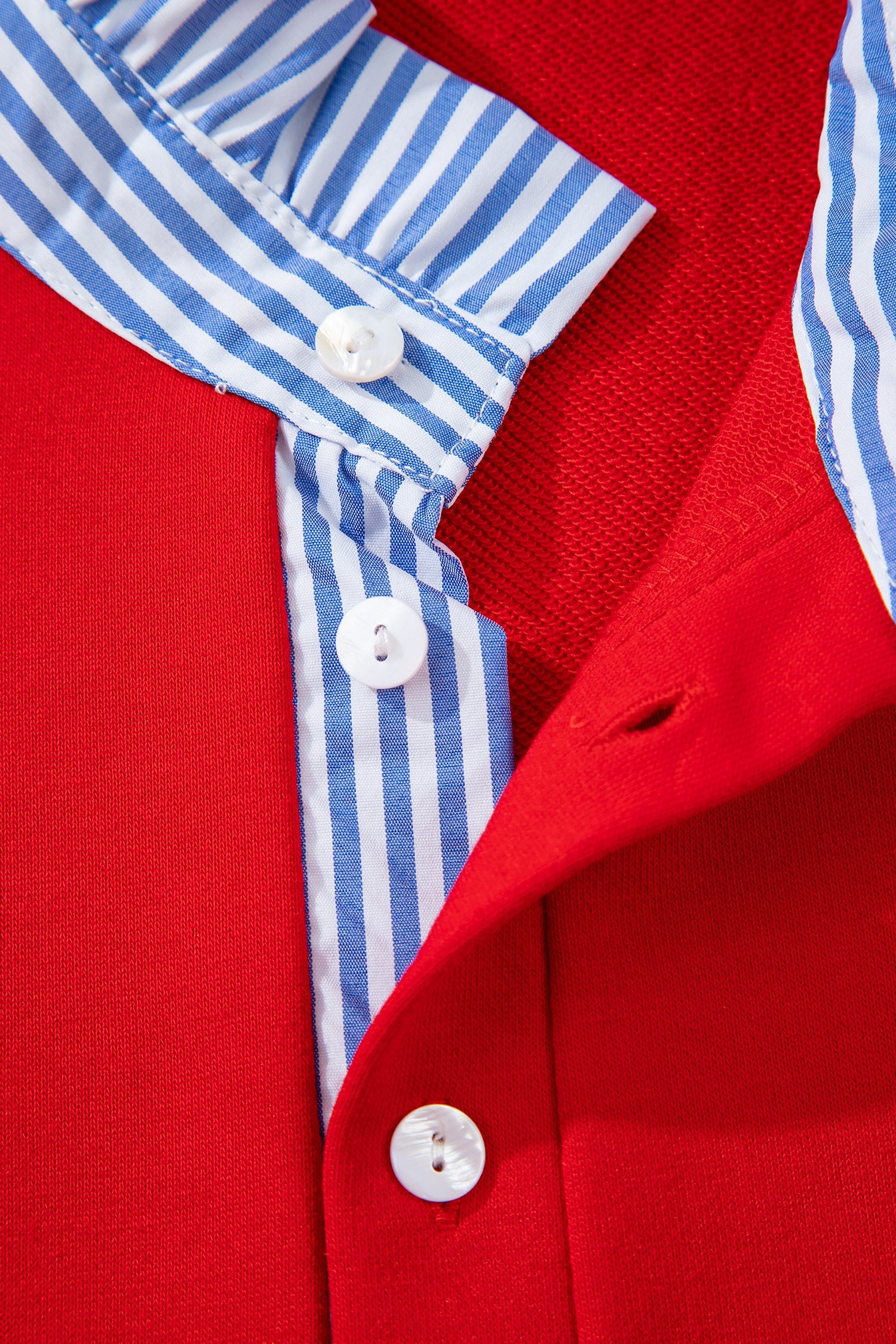 Close-up of red shirt with blue and white striped button placket and white buttons