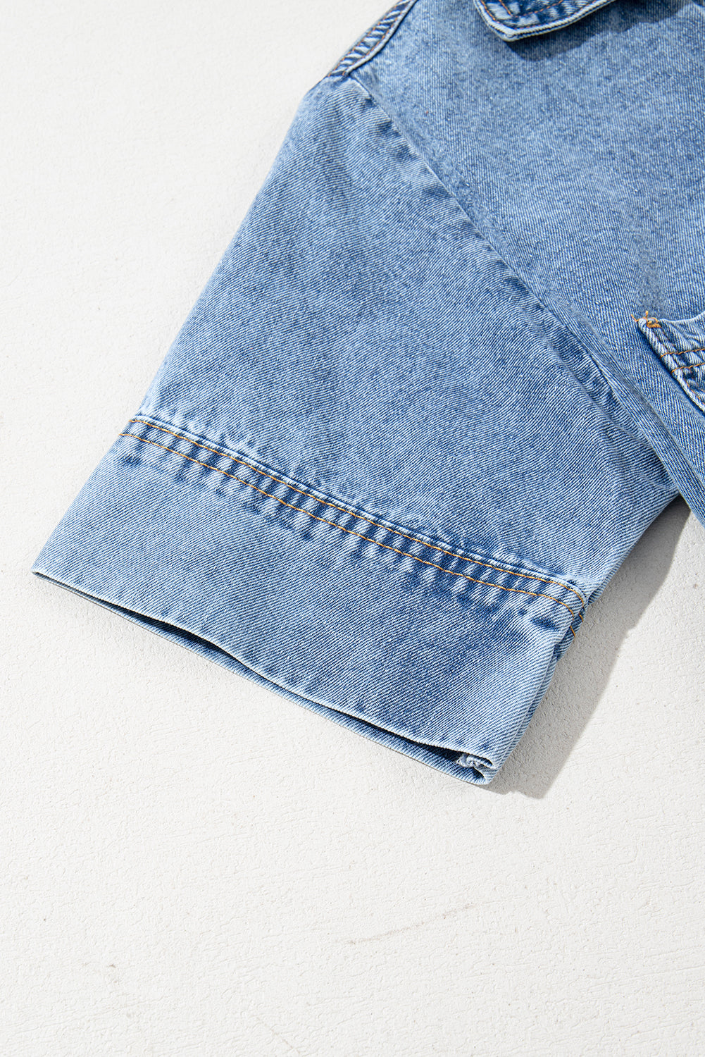 Close-up of light blue denim short sleeve with visible stitching detail