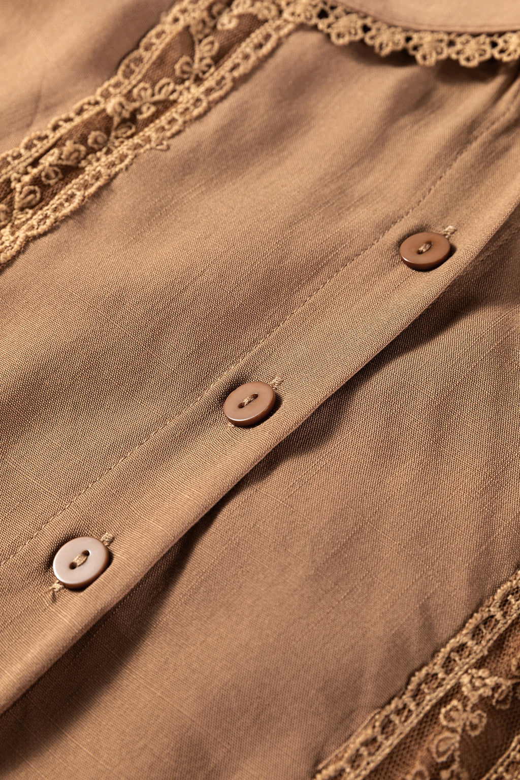 Close-up of a brown blouse with buttons and lace trim detail