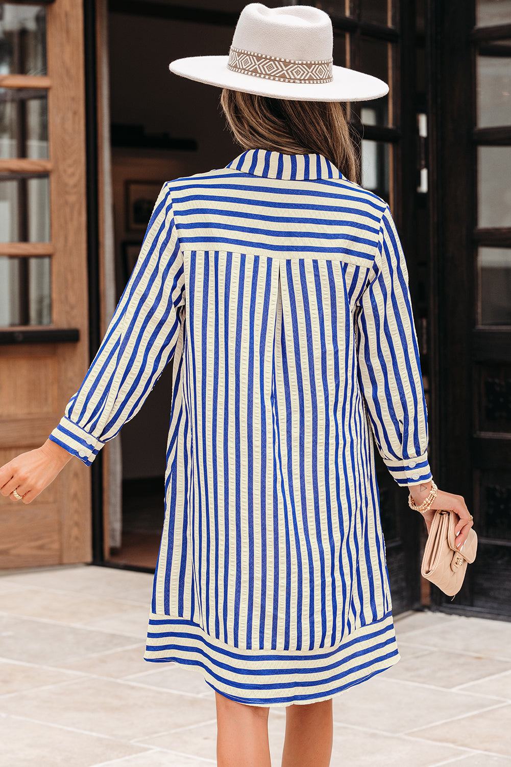 Woman in blue and white striped shirt dress with long sleeves and white wide-brim hat