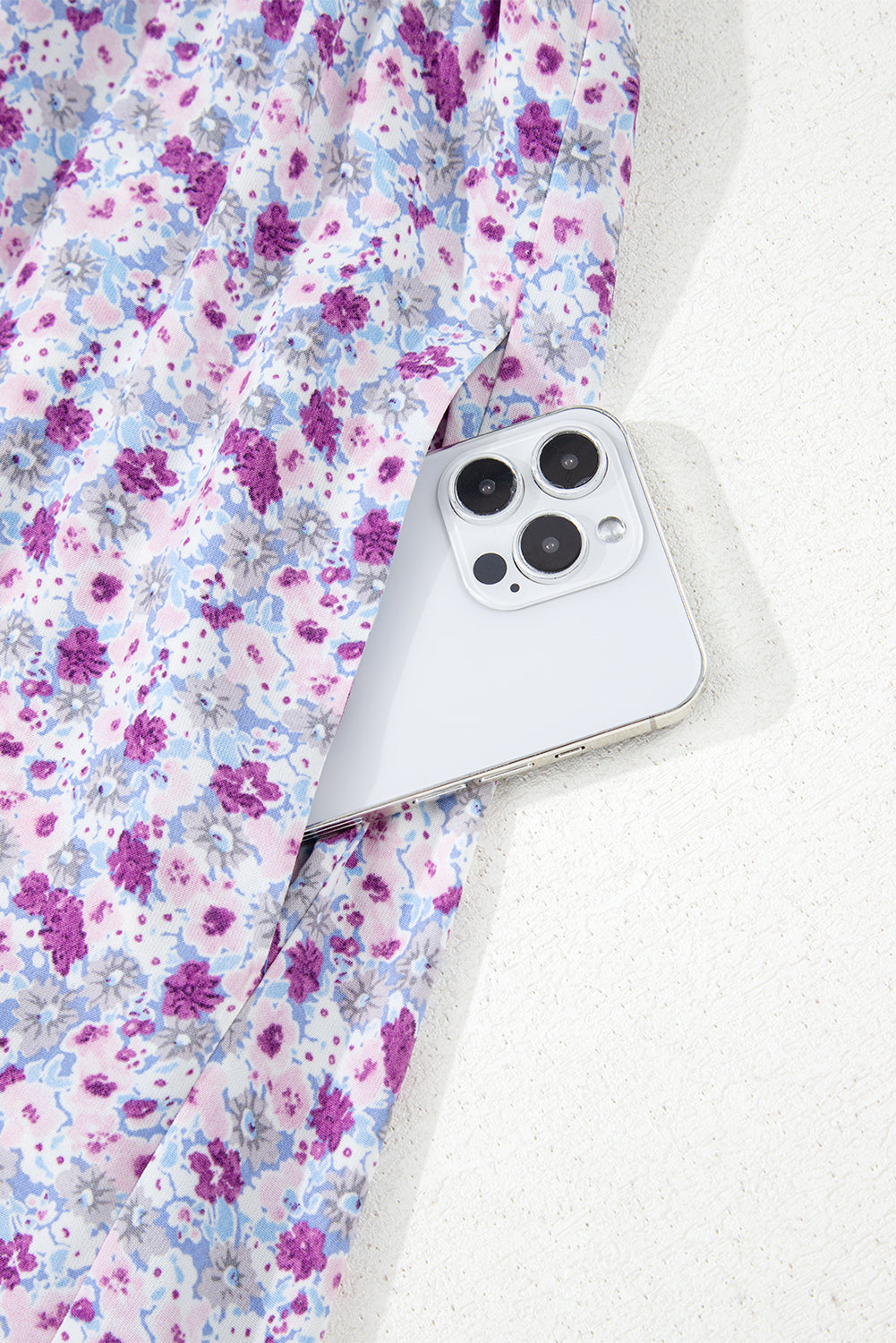 White smartphone in pocket of floral purple and blue patterned fabric skirt