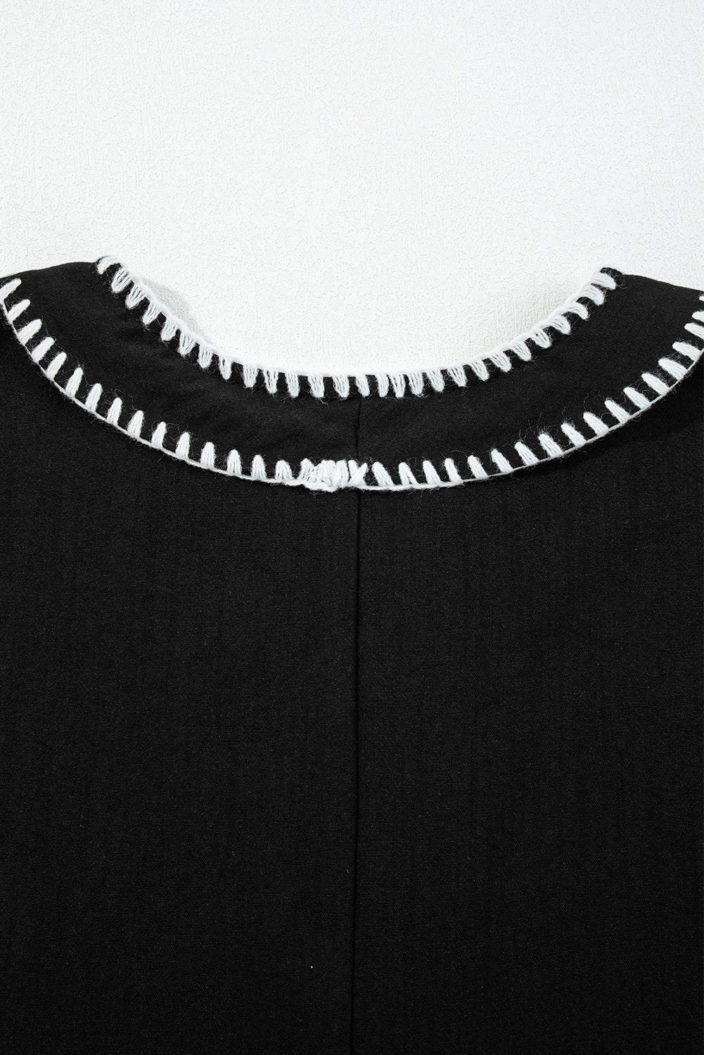 Black garment back neckline with white contrast stitch detailing