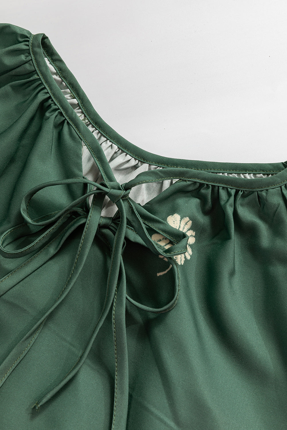 Green satin blouse with front tie detail and floral embroidery on neckline