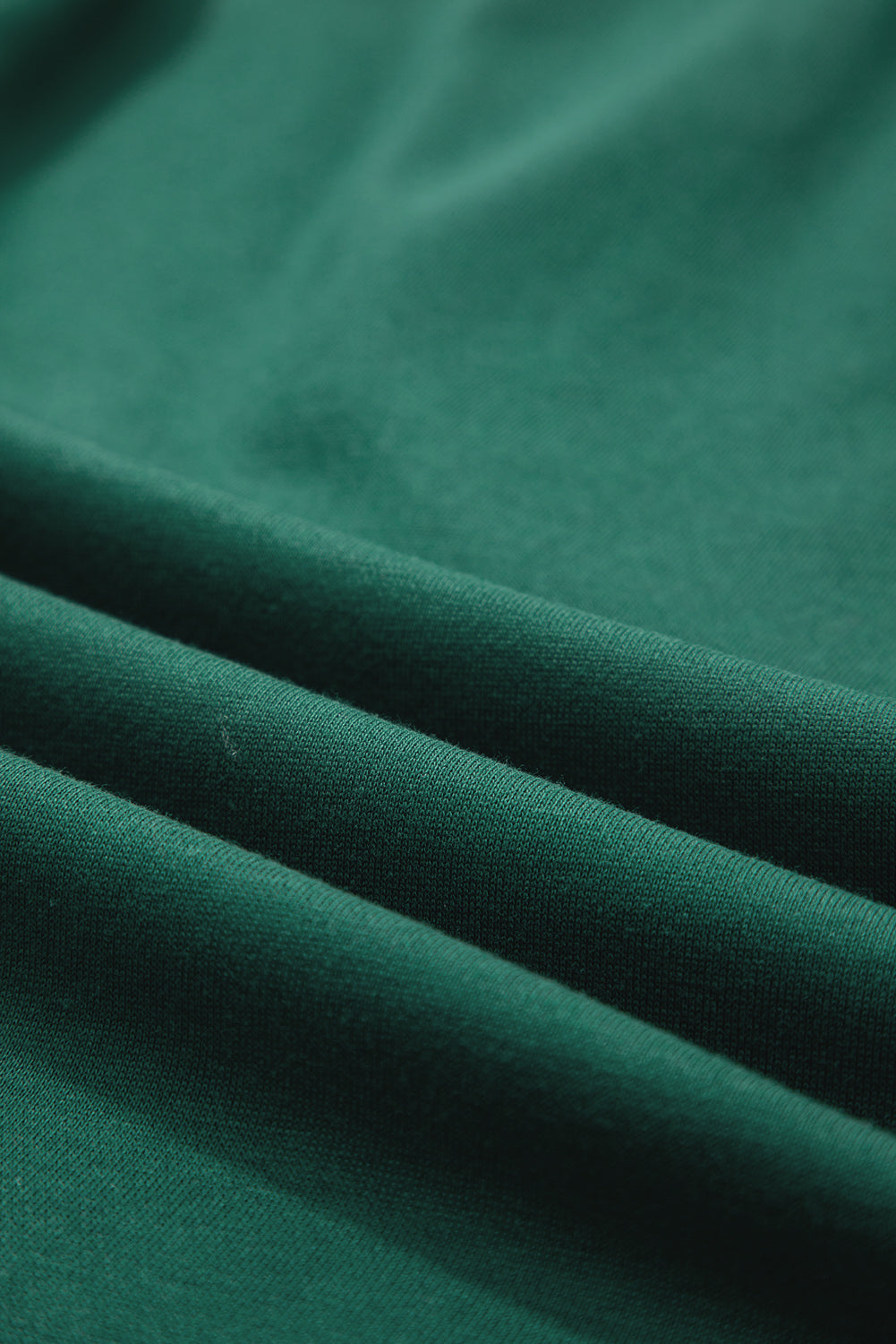 Close-up of green fabric texture with soft folds, textile material detail