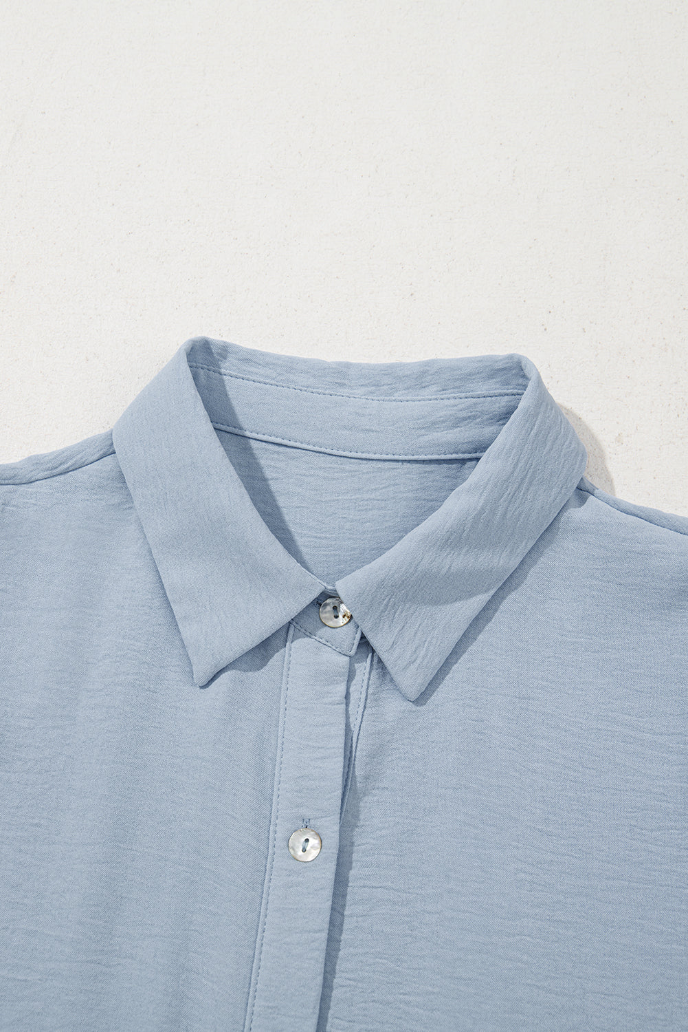 Light blue button-up shirt with spread collar and textured fabric on white background