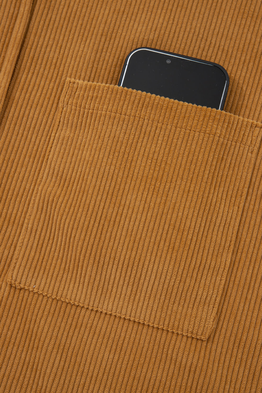 Brown corduroy shirt pocket with a black smartphone inside