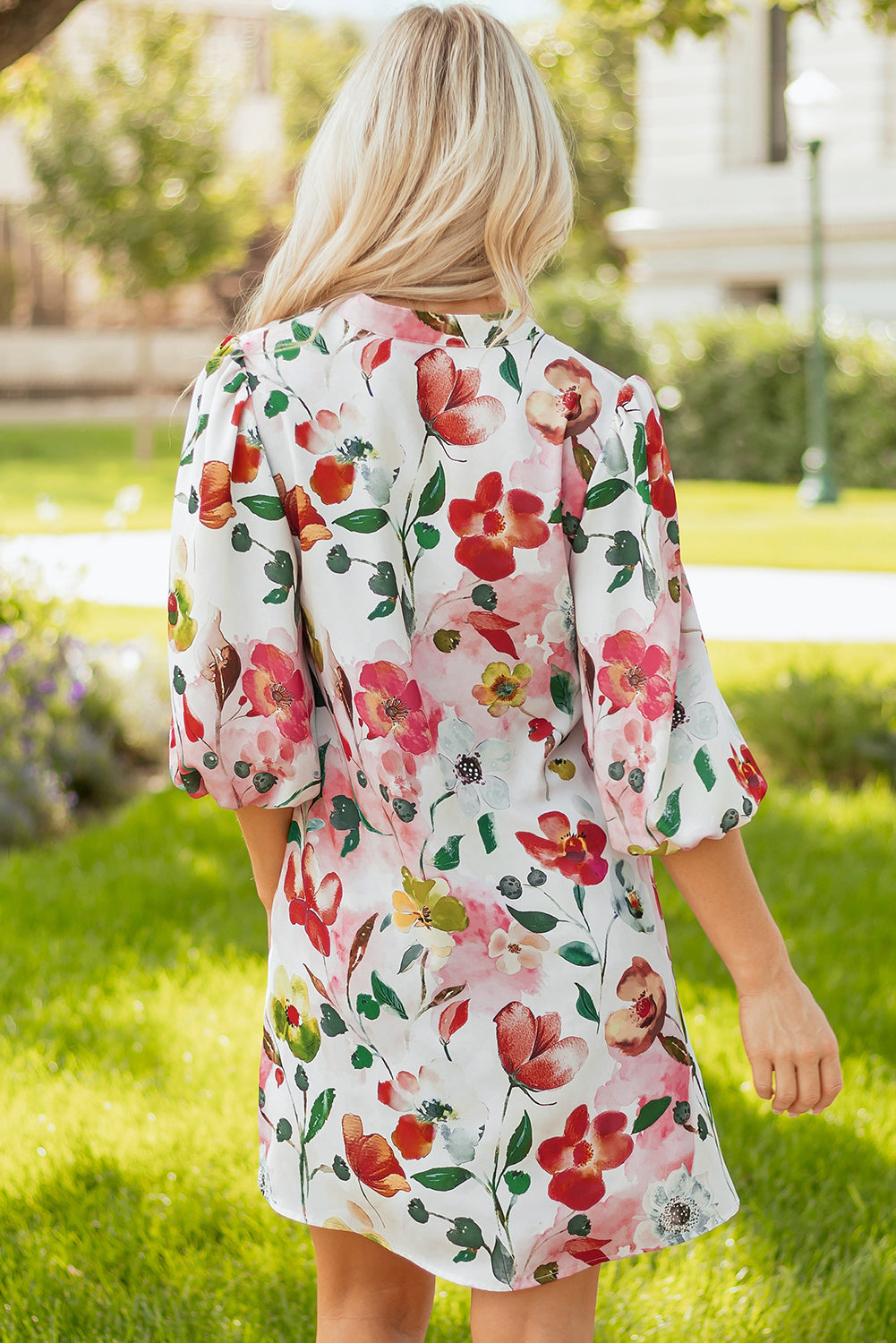 Woman outdoors wearing a white floral mini dress with colorful flower print and puff sleeves