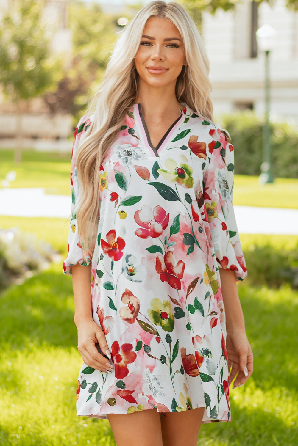 Woman in a white floral print dress with three-quarter sleeves standing outdoors