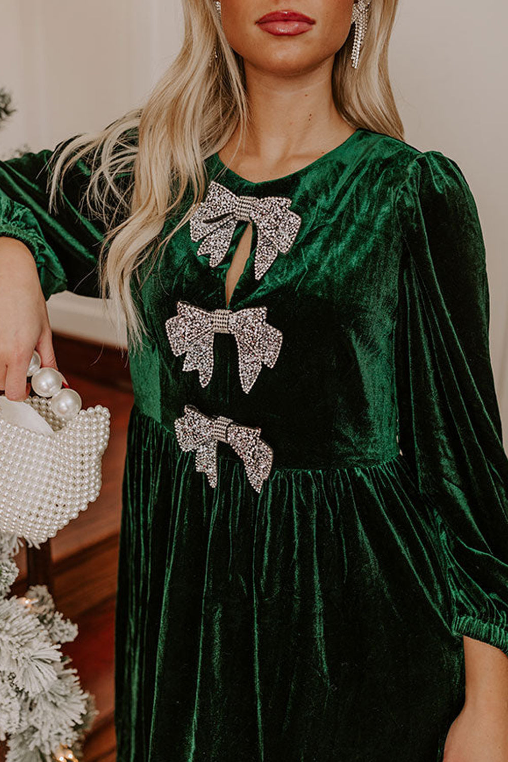 Green velvet dress with rhinestone bow accents and pearl beaded handbag