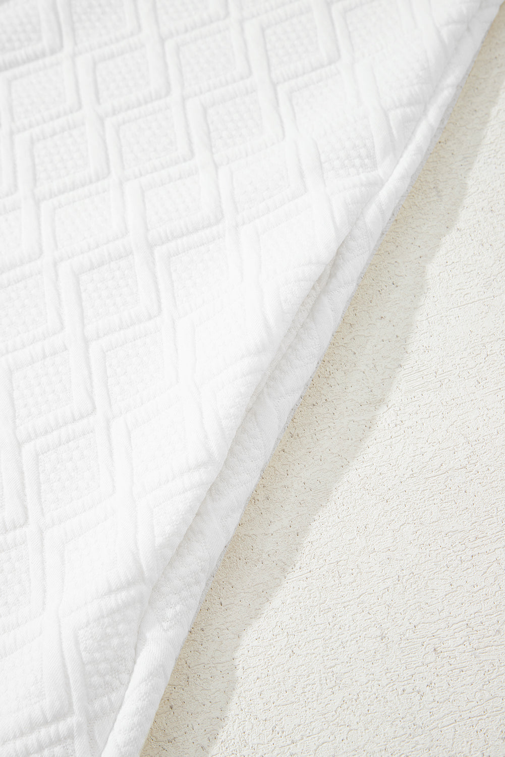 White textured fabric with geometric square pattern on a light surface