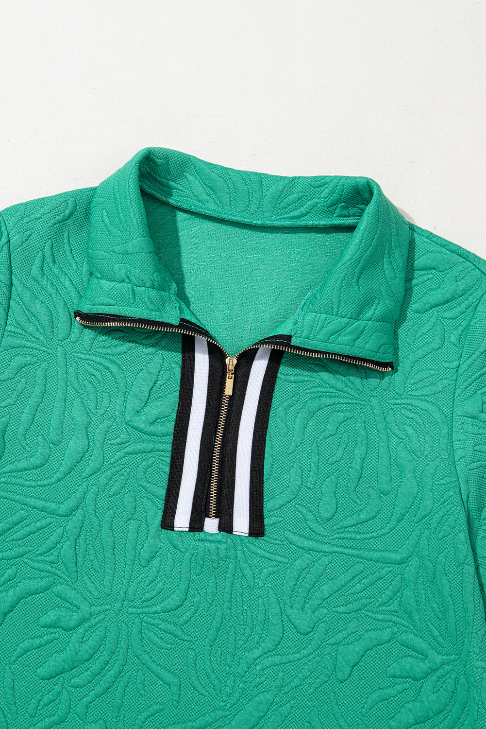 Green textured quarter-zip sweater with black and white striped zipper detail