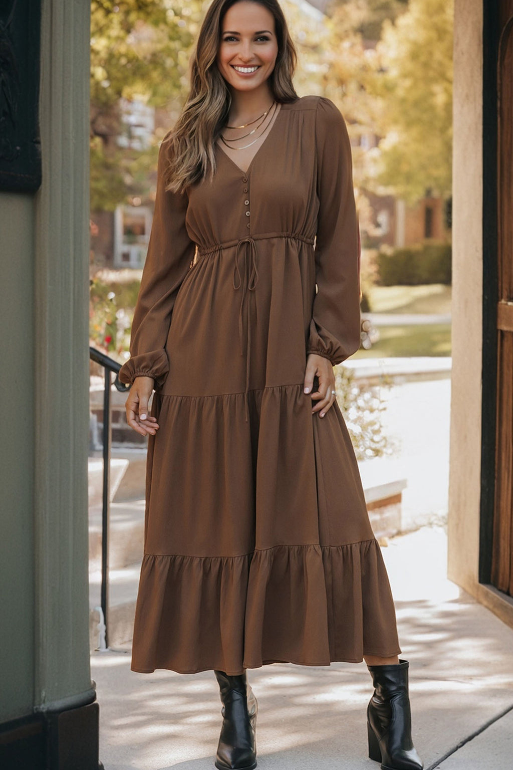 Woman wearing a brown long sleeve tiered maxi dress with black boots outdoors