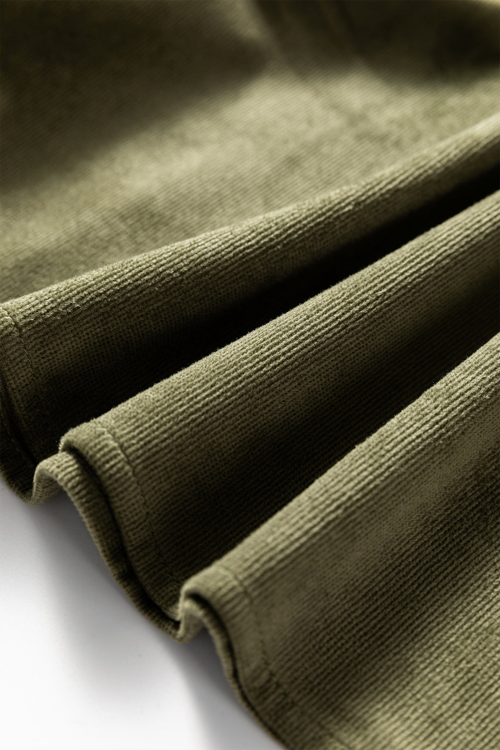 Close-up of olive green ribbed fabric with soft texture and folded edges