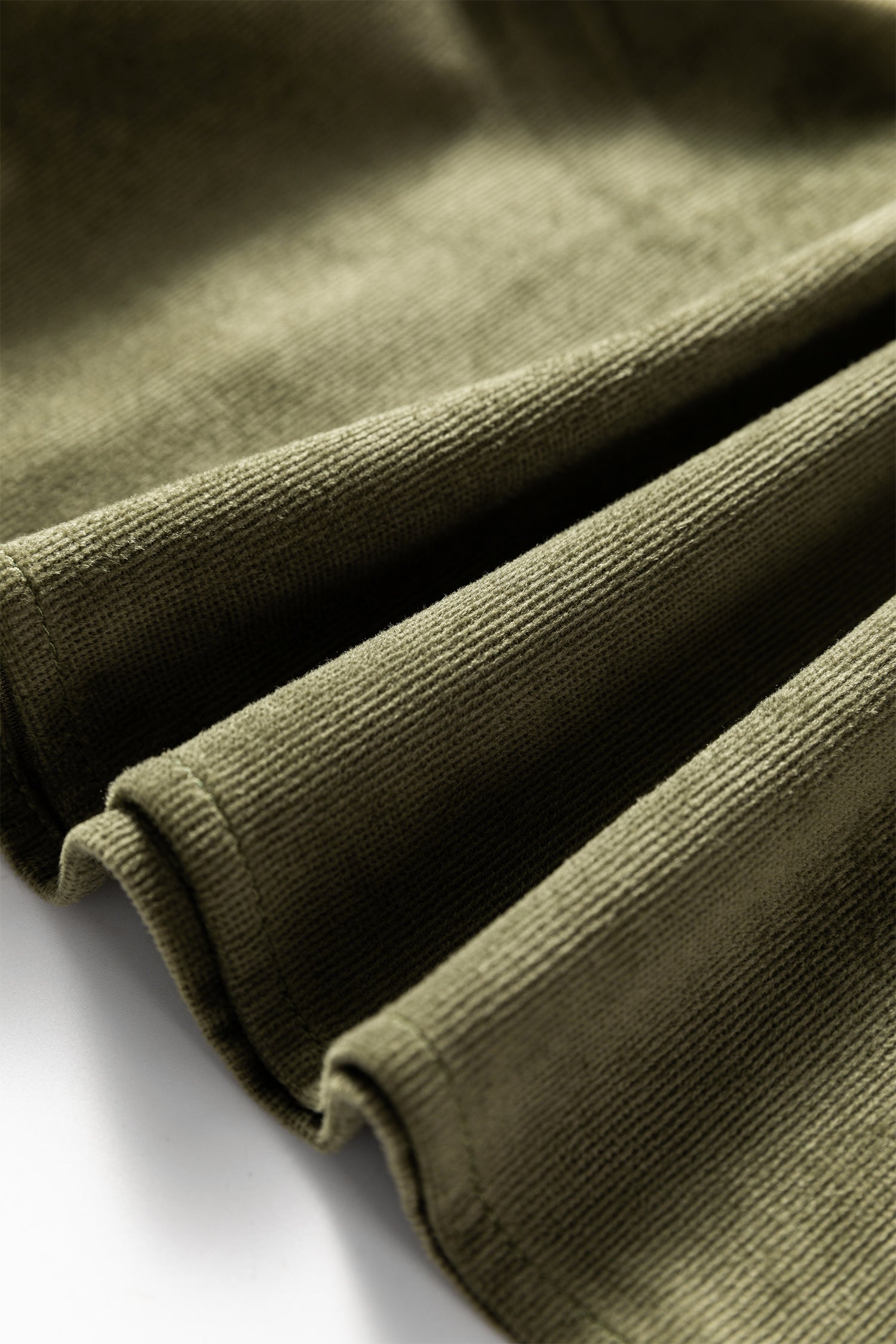 Close-up of olive green ribbed fabric with soft texture and folded edges