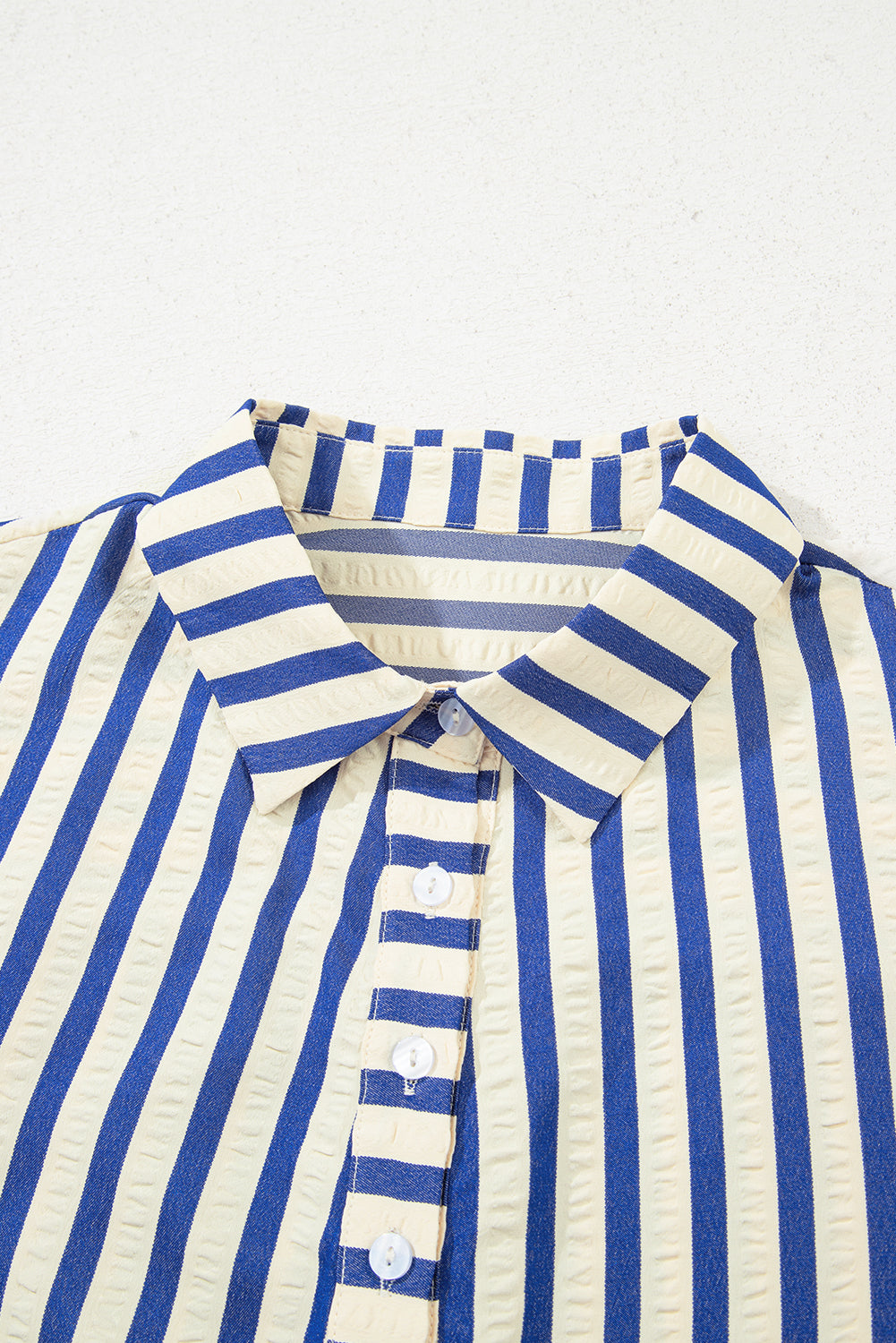 Blue and cream vertical striped shirt with collar and white buttons, textured fabric