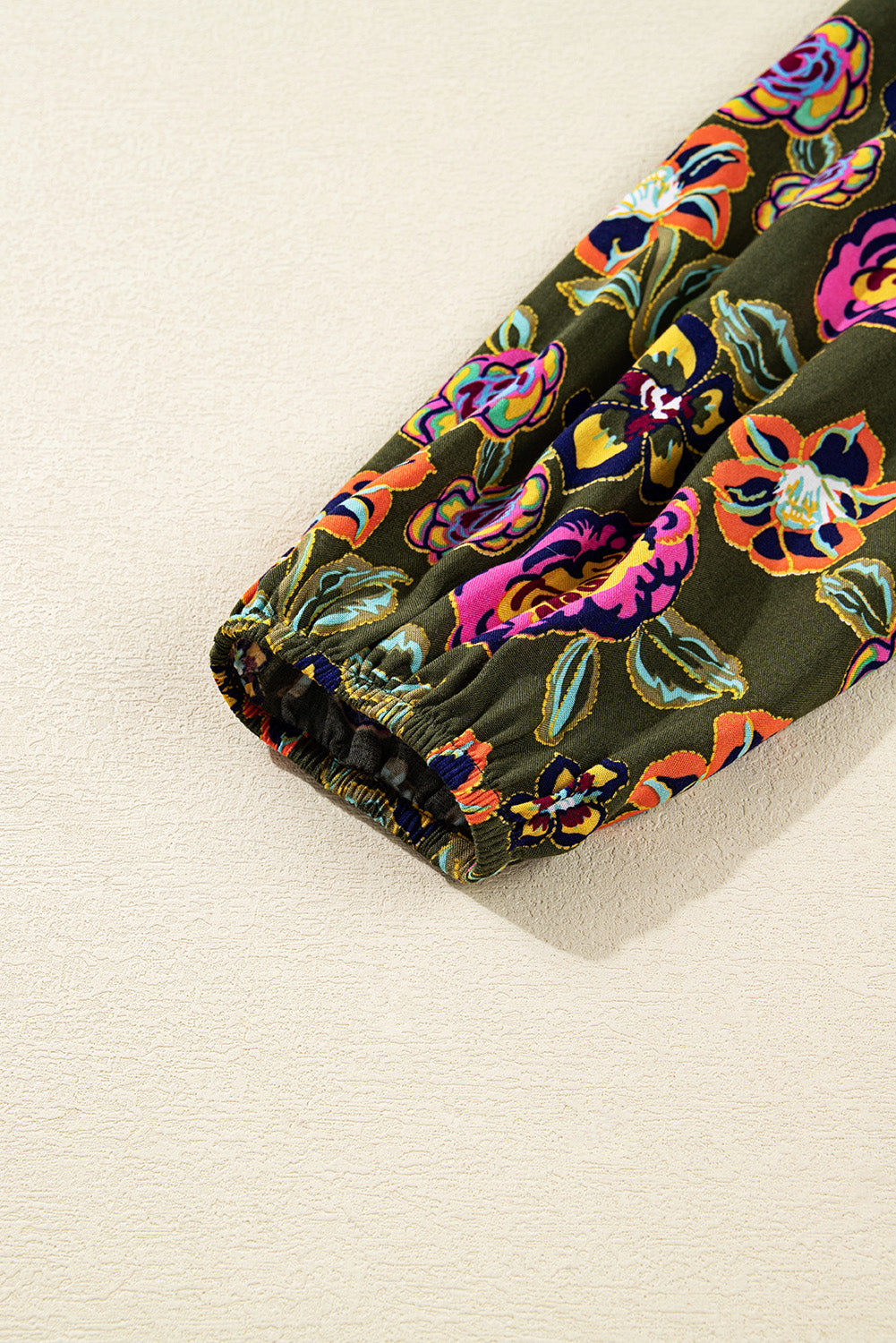 Close-up of floral print sleeve with elastic cuff on green fabric