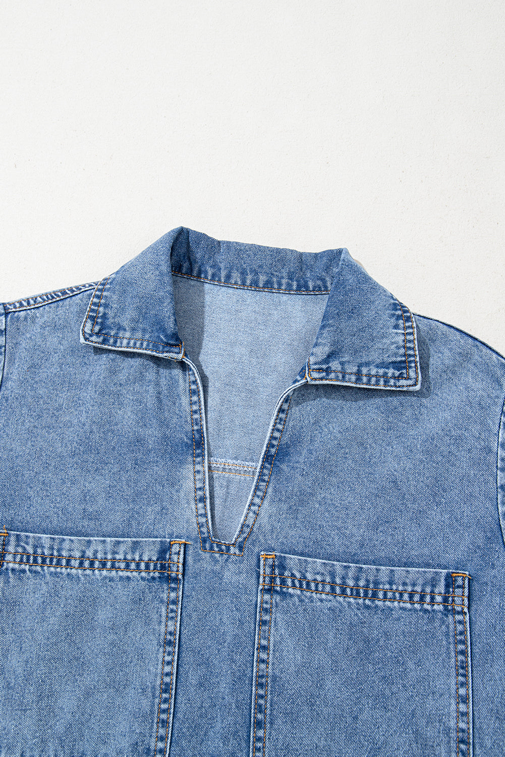 Light blue denim shirt with collar, V-neck, and front chest pockets on a white background