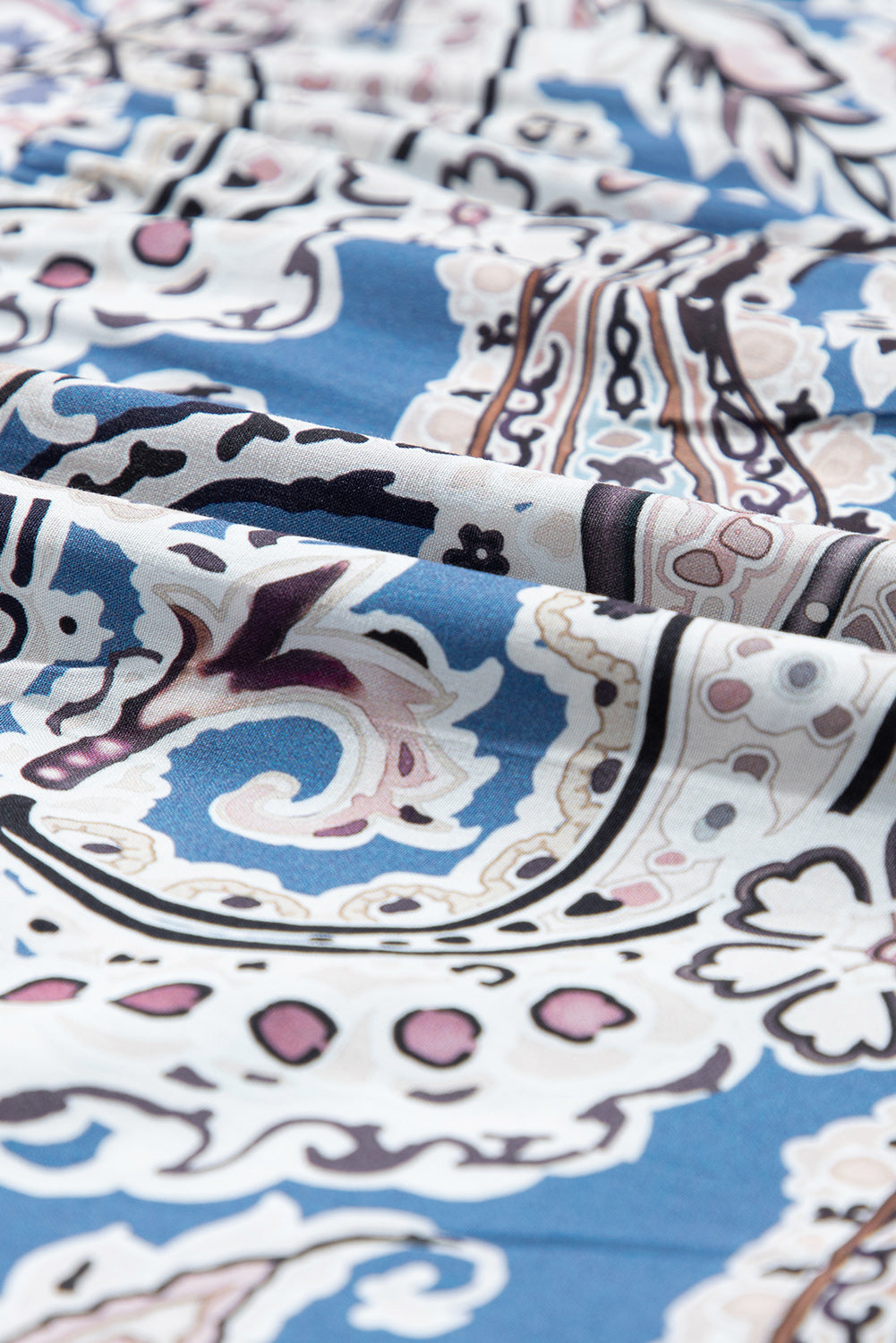Close-up of blue paisley patterned fabric with white and pink details, soft texture