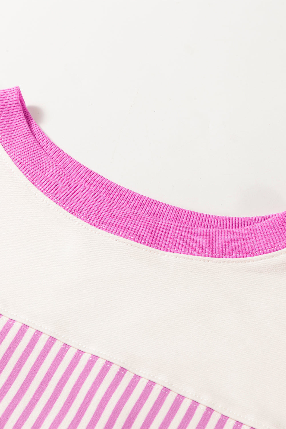 Close-up of a shirt with a pink ribbed collar and pink and white striped fabric