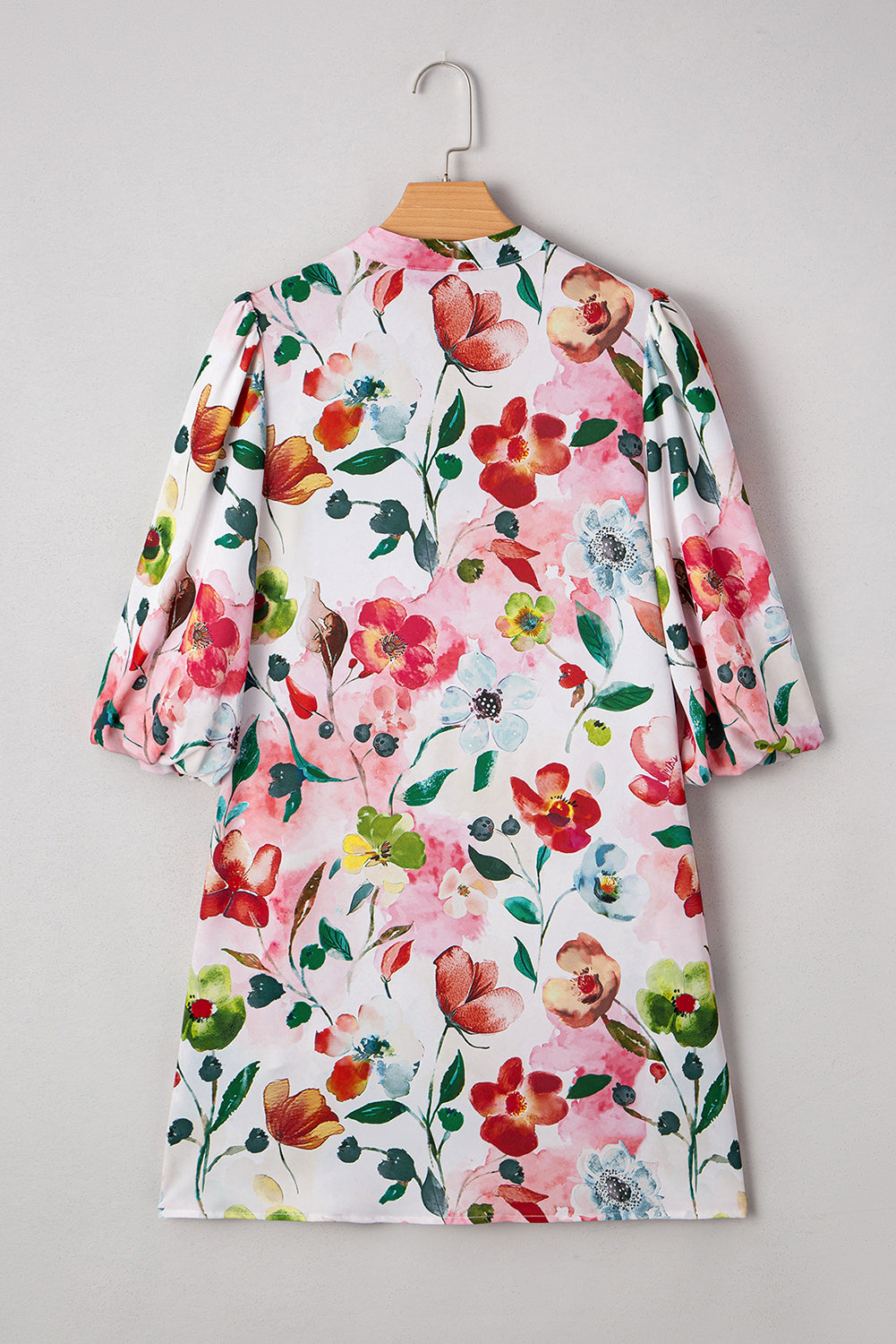 Floral print dress with puff sleeves and watercolor flowers on white background, hanging on hanger