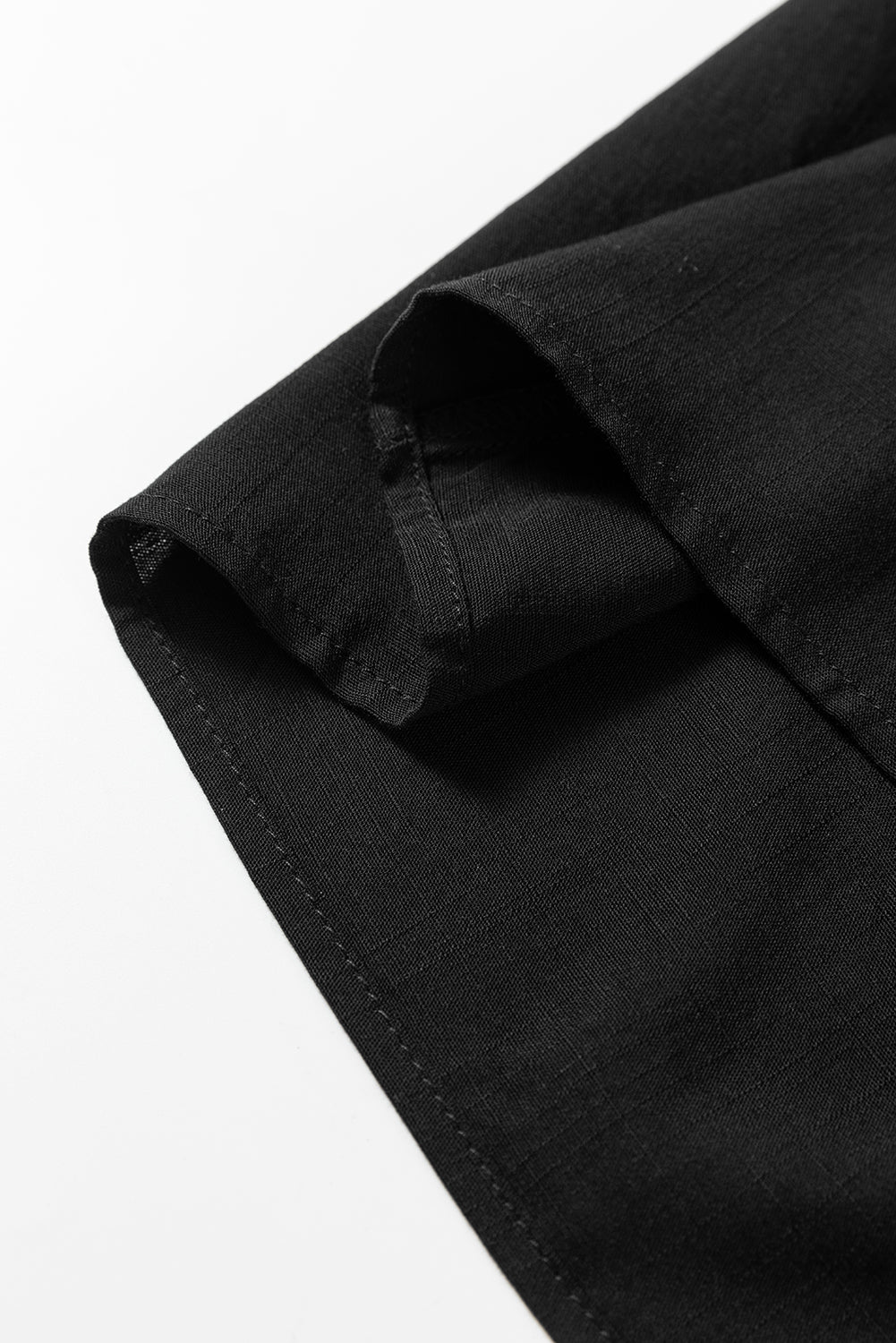 Close-up of black linen fabric with visible stitching and clean hem on white background