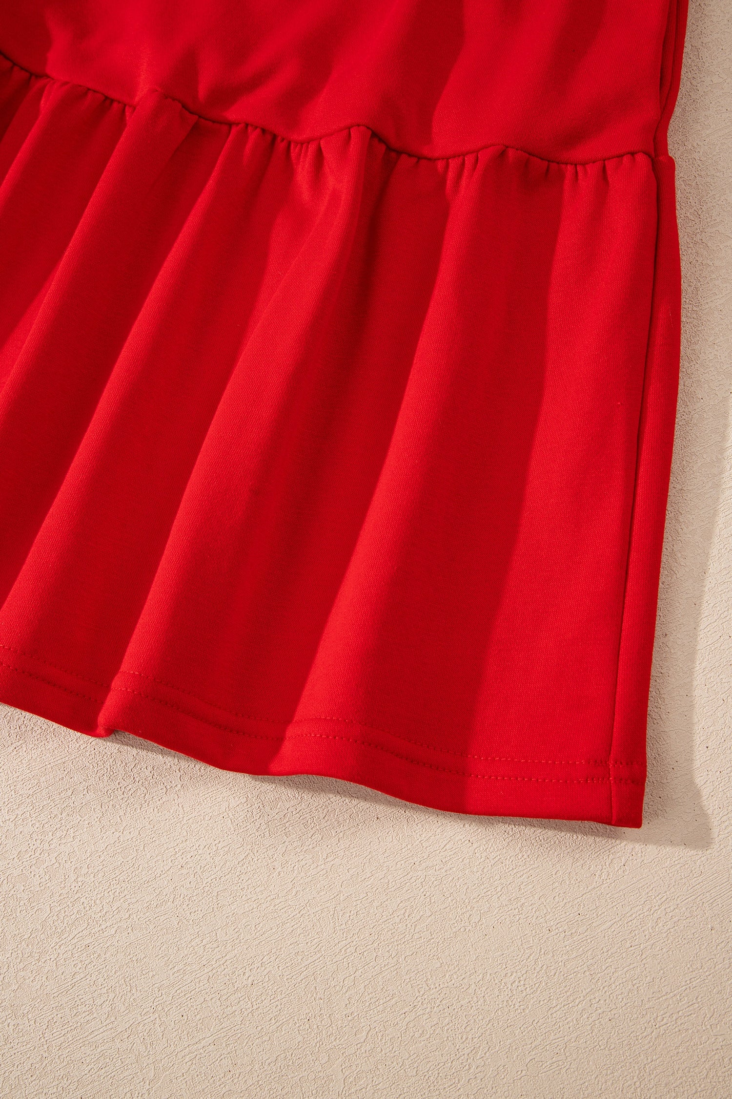 Close-up of red ruffle hem dress fabric on beige textured background