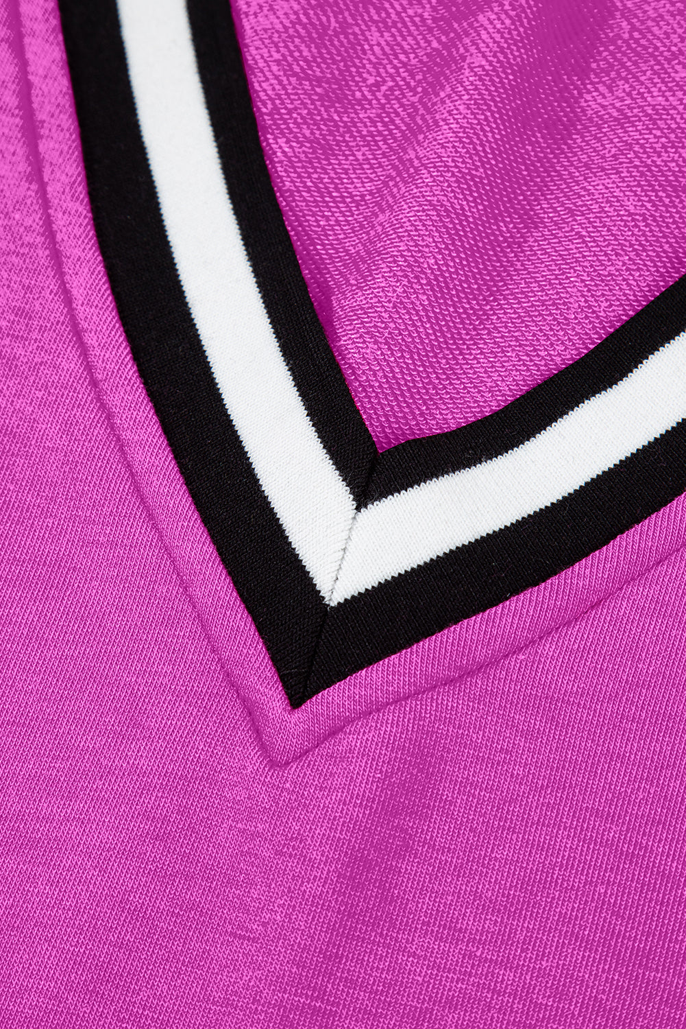 Close-up of pink fabric with V-shaped black and white striped trim, sporty textile detail
