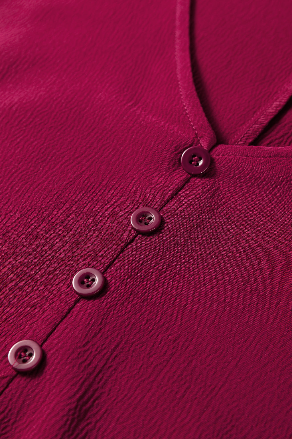 Close-up of textured burgundy blouse with buttons and V-neck, women’s fashion top
