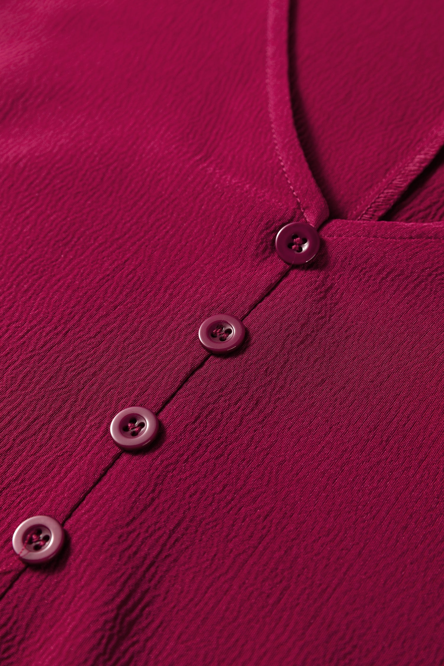 Close-up of textured burgundy blouse with buttons and V-neck, women’s fashion top