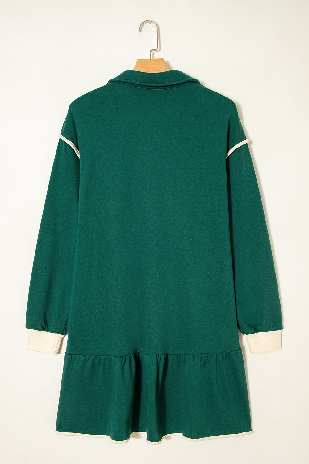 Back view of a green long sleeve dress with white cuffs and shoulder trim, ruffled hem