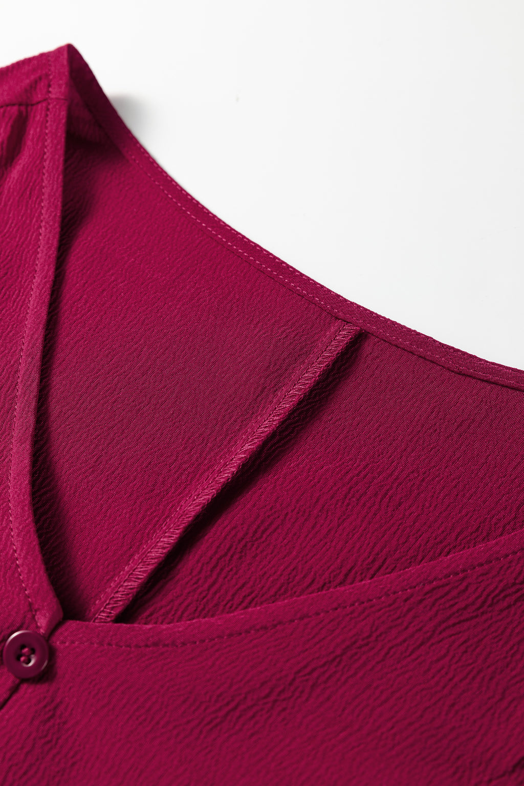 Textured magenta V-neck blouse with button detail and sheer insert close-up
