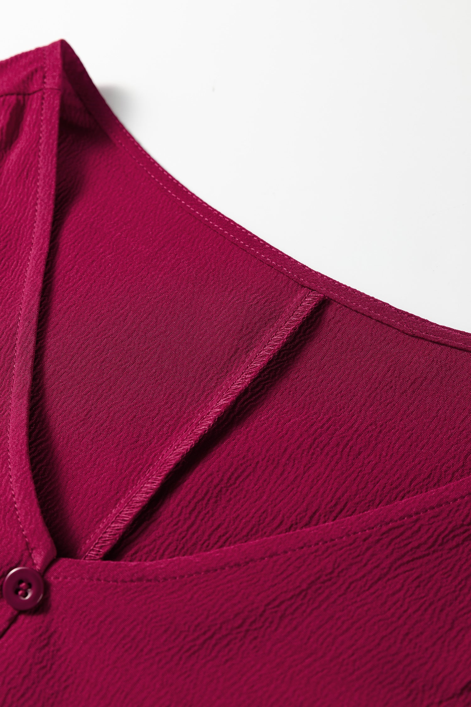 Textured magenta V-neck blouse with button detail and sheer insert close-up