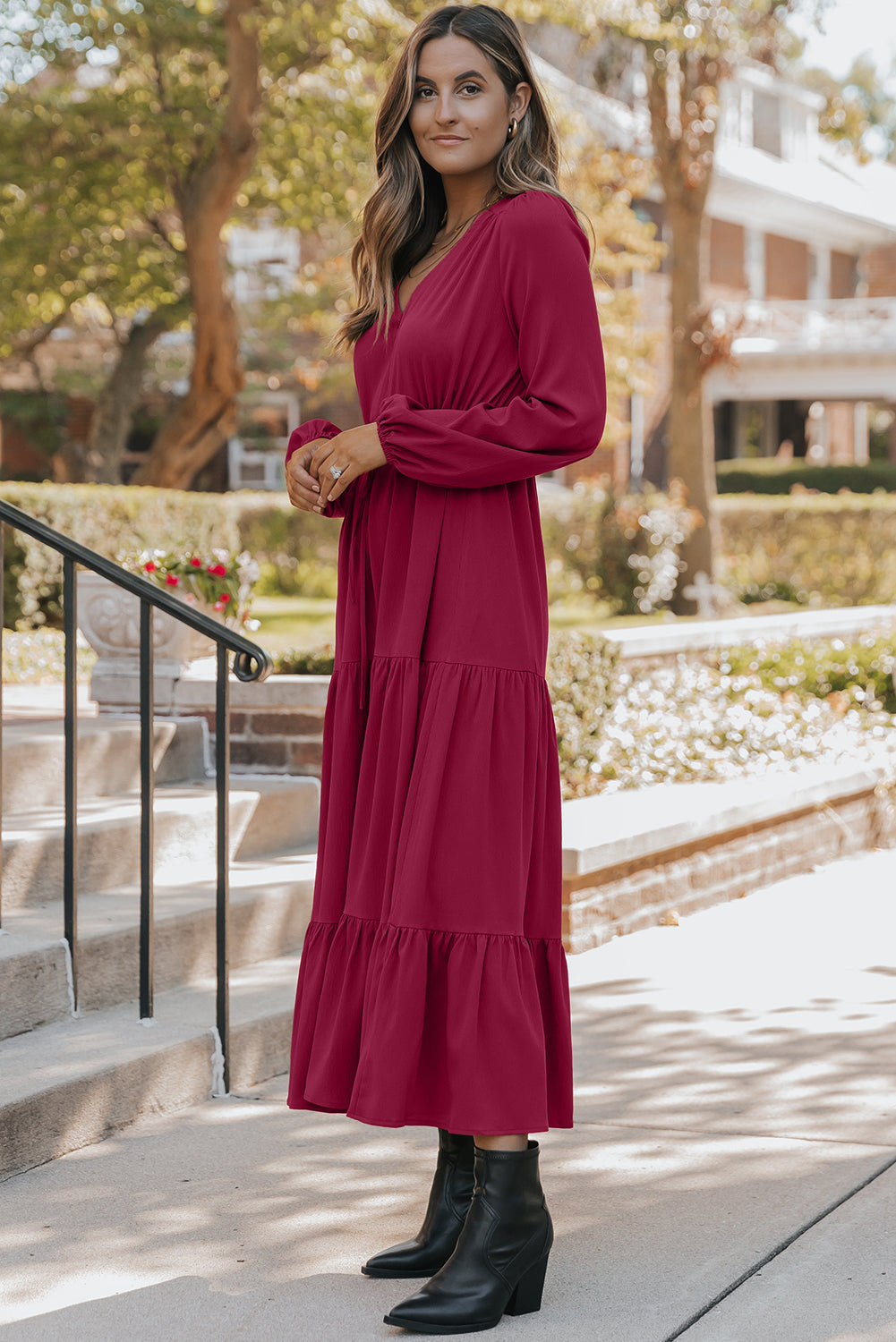 Woman wearing a long-sleeve burgundy tiered dress and black ankle boots outdoors