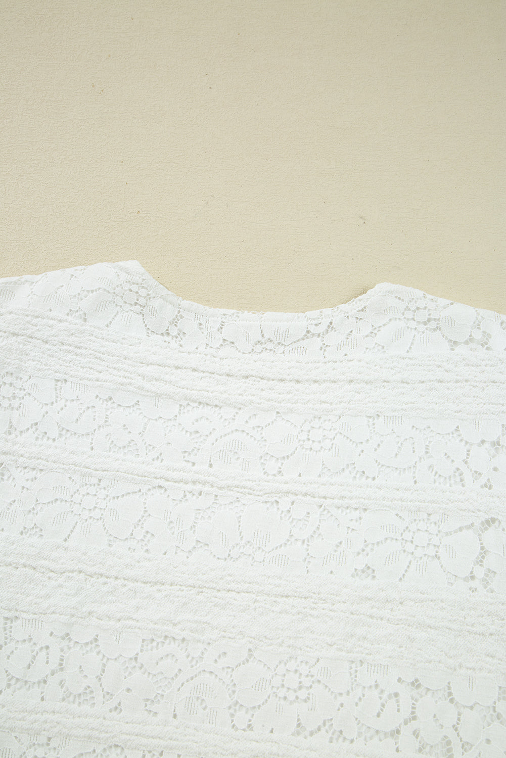 Close-up of a white lace fabric with floral patterns and textured stripes