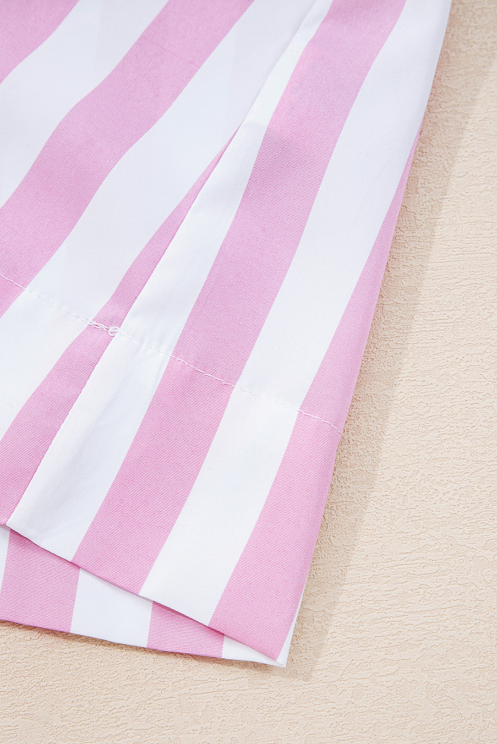 Close-up of pink and white vertical striped fabric on a light textured surface