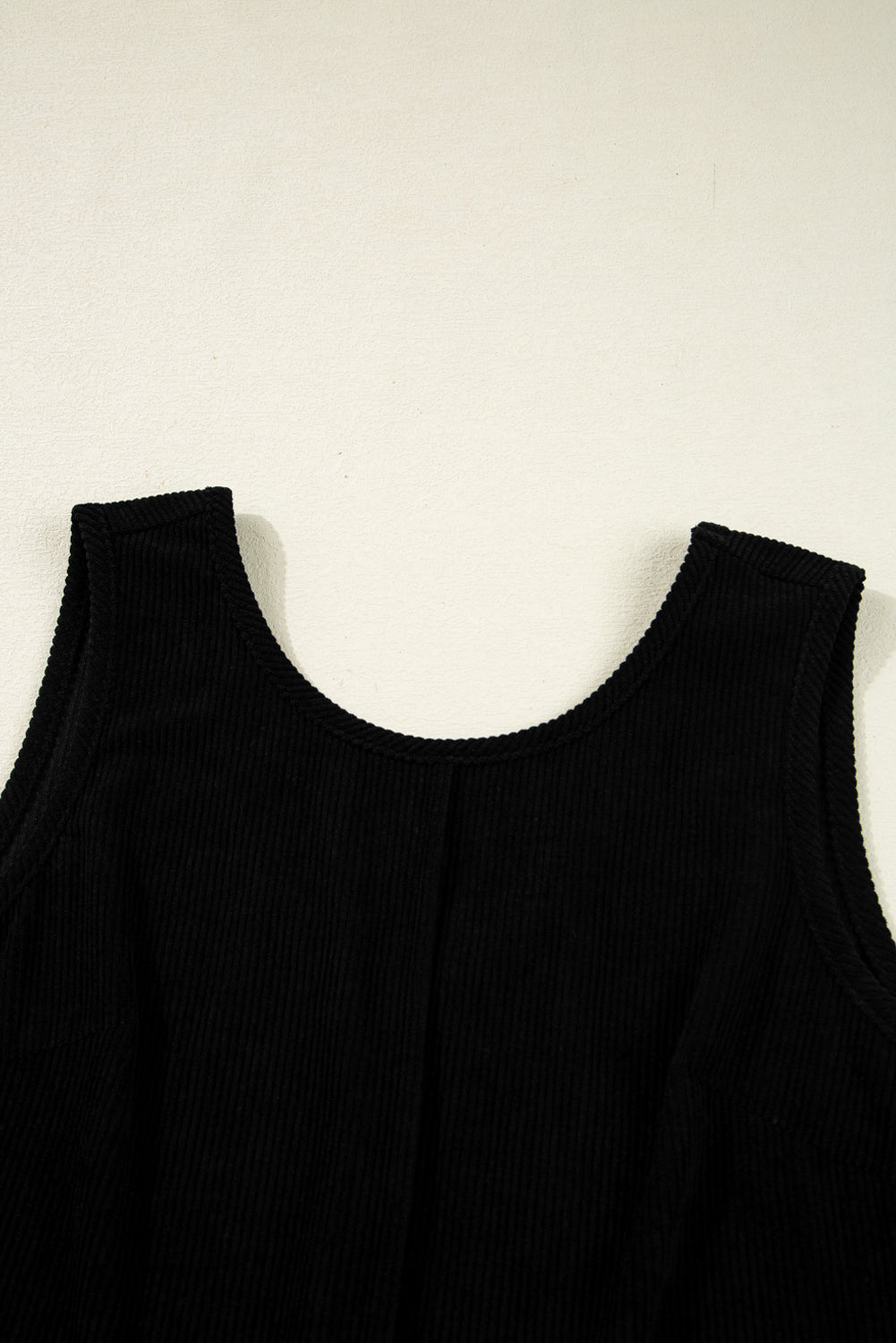 Black ribbed sleeveless top with round neckline on light background