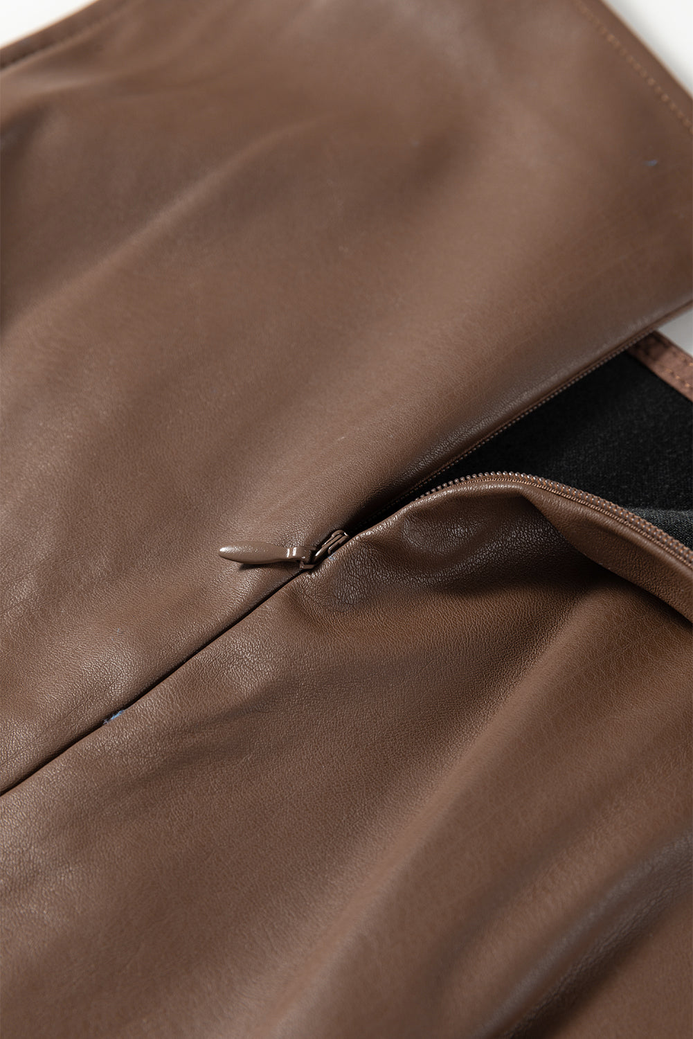 Close-up of brown faux leather garment with zipper detail