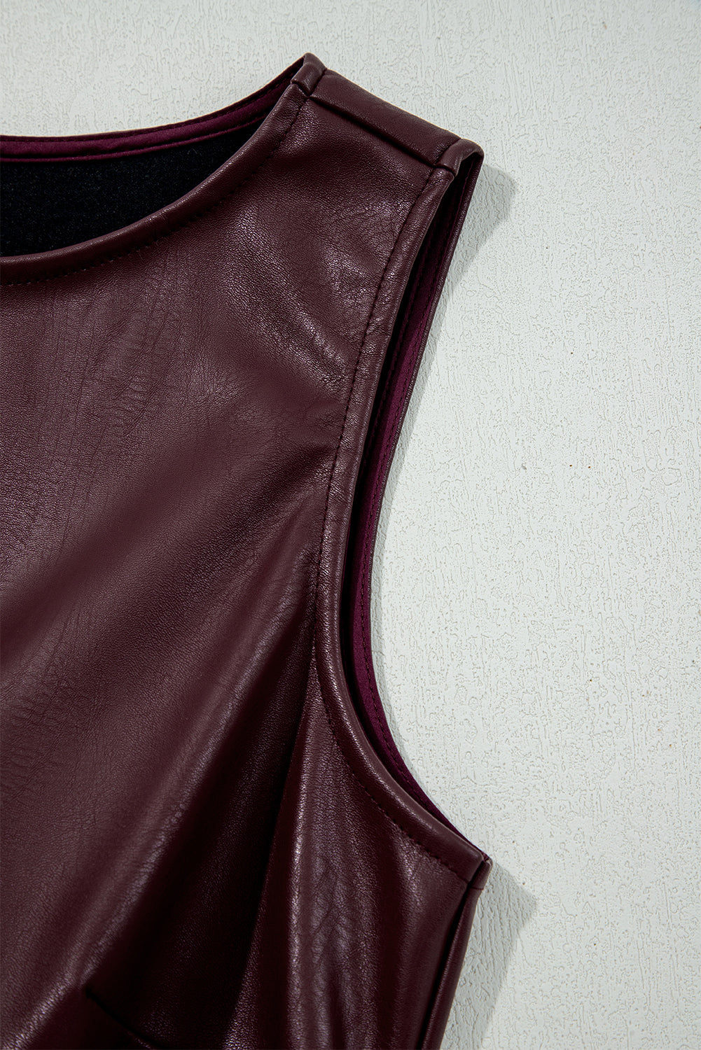 Close-up of a sleeveless burgundy faux leather top with a round neckline