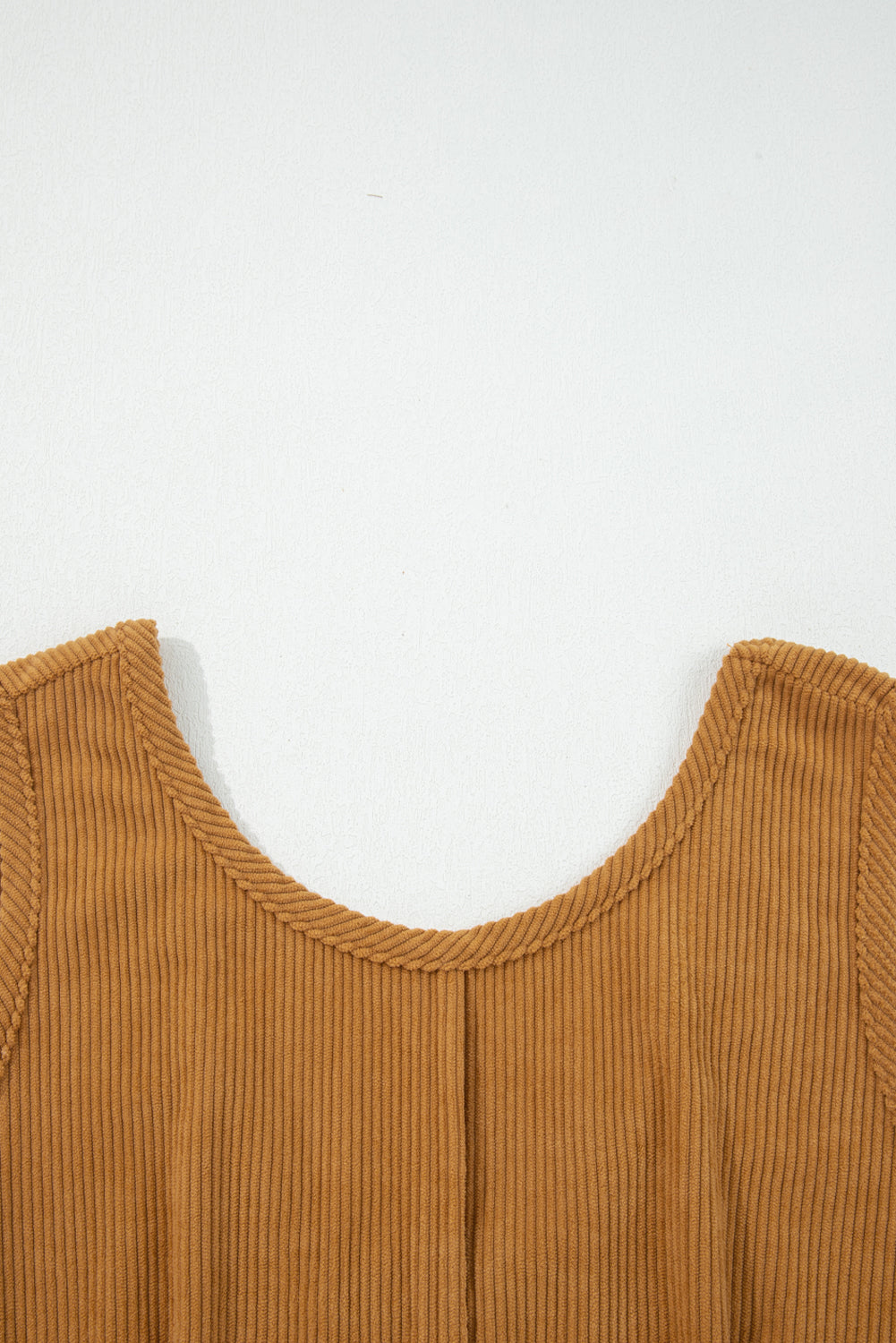 Close-up of ribbed corduroy sleeveless brown top with round neckline on white background