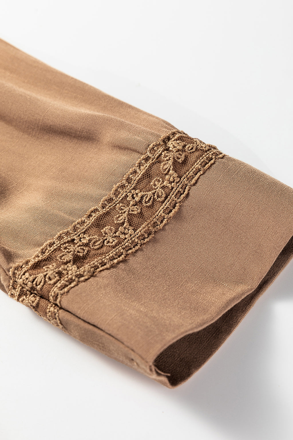 Close-up of brown sleeve with floral lace trim, elegant women's clothing detail