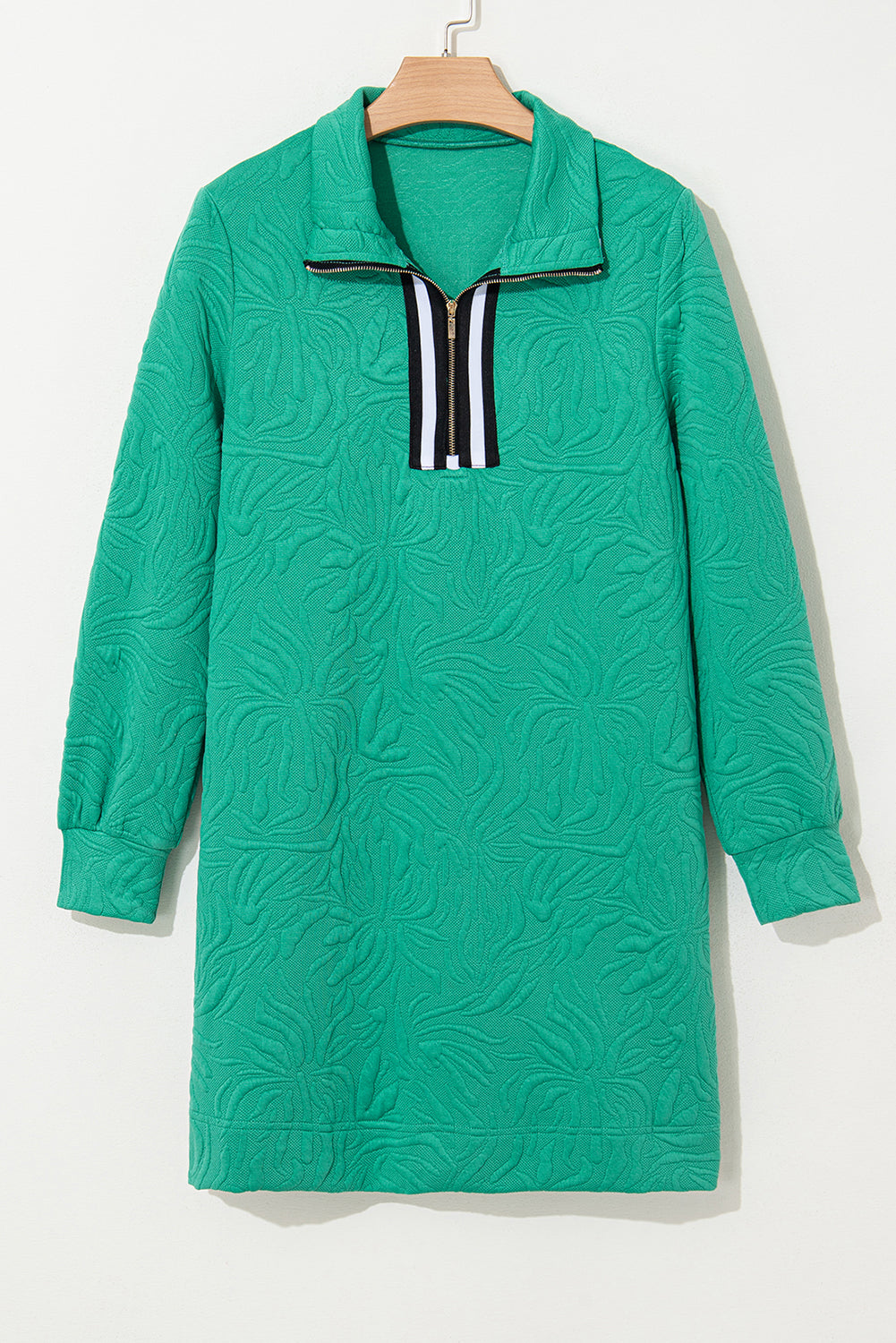 Green textured long sleeve dress with zip collar and black white trim, hanging on hanger