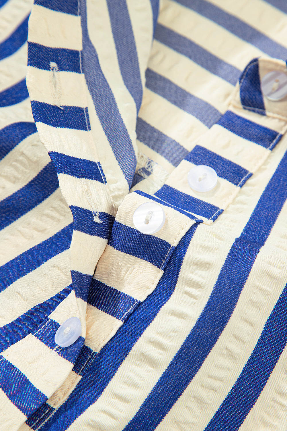 Close-up of blue and white striped shirt with textured fabric and white buttons