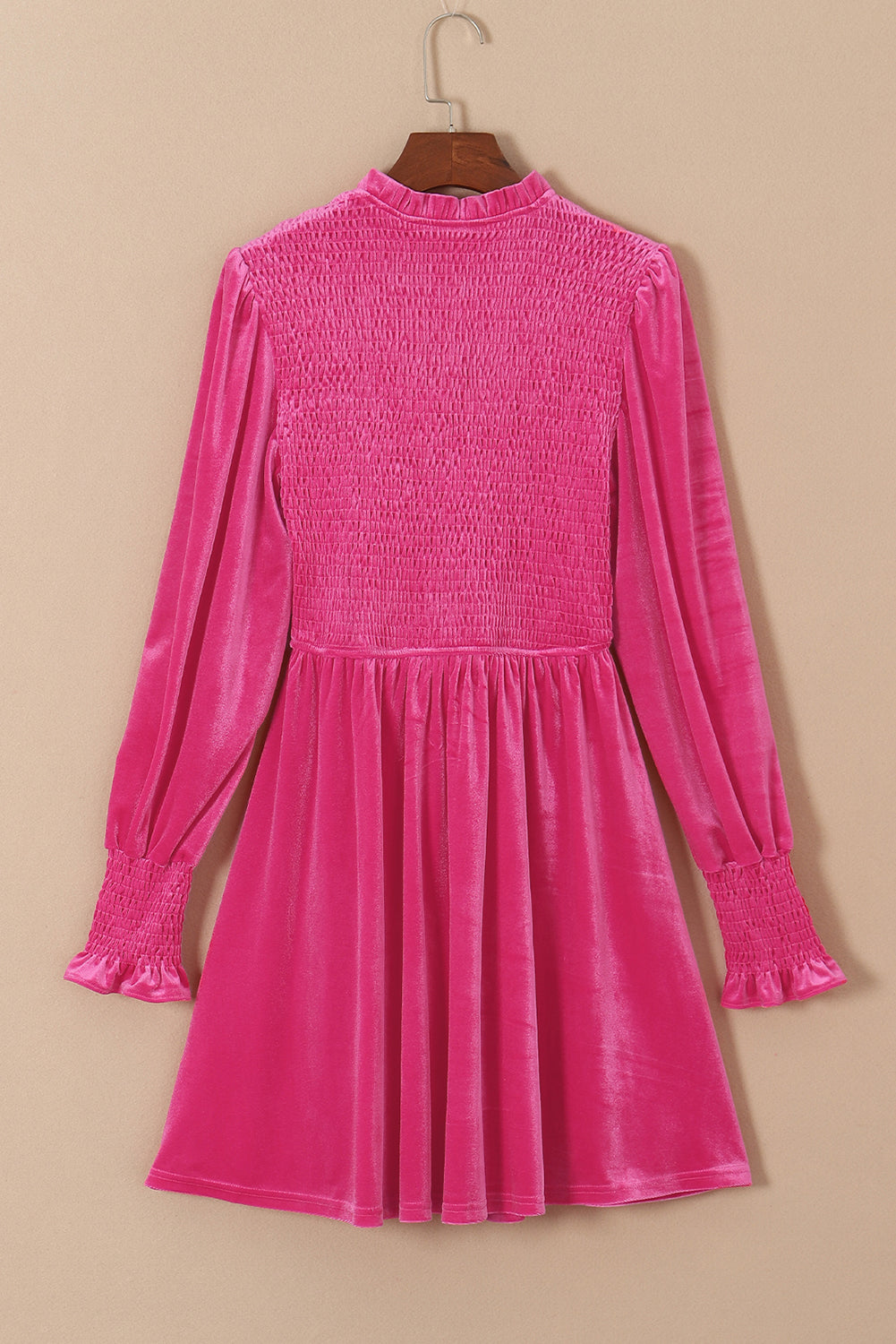 Pink velvet long sleeve mini dress with smocked bodice and ruffled cuffs on hanger