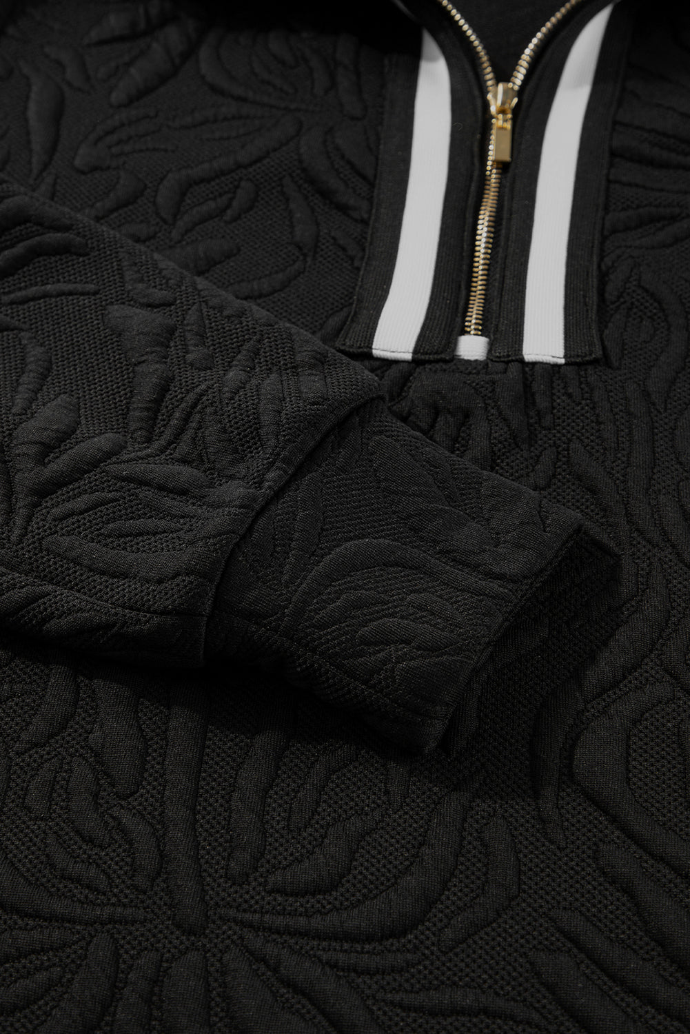 Black textured sweatshirt with embossed pattern, gold zipper, and white stripe detailing