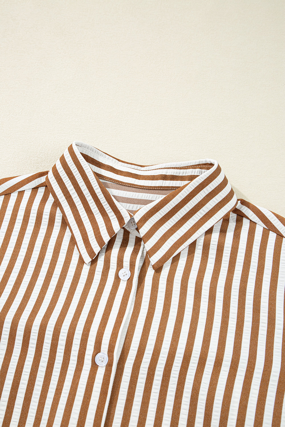 Brown and white vertical striped button-up shirt with classic collar on beige background