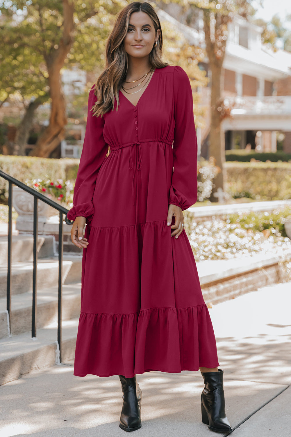 Woman wearing a long sleeve burgundy maxi dress with ruffle details, black ankle boots, outdoor setting