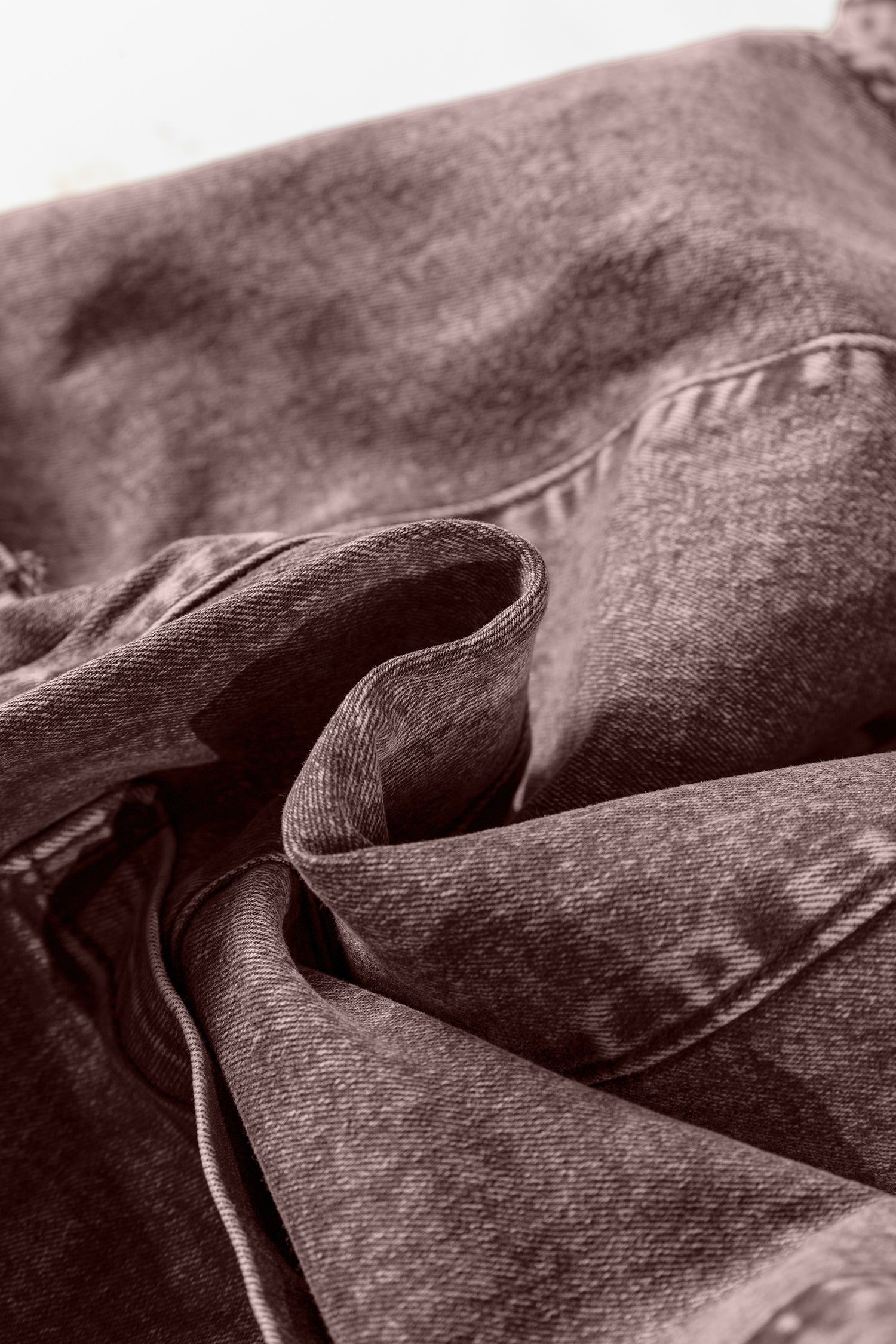 Close-up of folded denim fabric with visible seams and textured textile surface